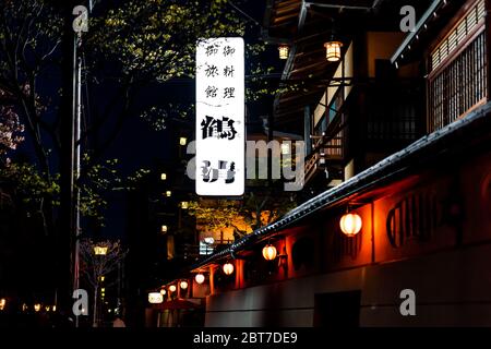 Kyoto, Japan - 16. April 2019: Schmale dunkle Straße in der Nacht in Pontocho Alley District mit beleuchteten Reihe von roten Papierlaternen und Schild für Restauraa Stockfoto