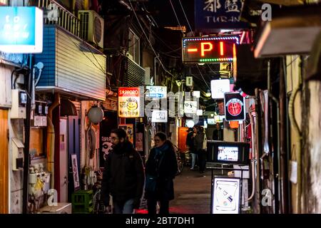 Tokio, Japan - 3. April 2019: Shinjuku im Stadtzentrum mit Leuten, die auf der schmalen Gai Gasse Straße mit Izakaya Restaurants in der Nacht und Stockfoto