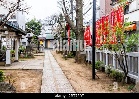 Tokio, Japan - 28. März 2019: Kaichu inari Shinto-Schrein in Shinjuku mit roten Bannern und Pfad im Garten und Reinigungsbrunnen mit niemand Stockfoto