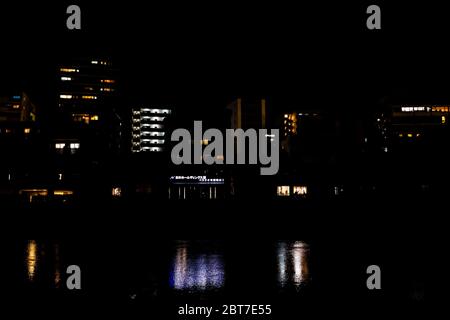 Kyoto, Japan - 9. April 2019: Beleuchtete Häuser am Flussufer spiegeln sich nachts am Kamo Fluss mit Hintergrund der Lichter Stadtlandschaft Stockfoto