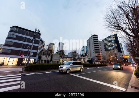 Shinjuku, Japan - 1. April 2019: Straße in der Innenstadt von Tokio mit Gebäuden während der blauen Stunde am Abend mit Autos im Verkehr in Okubo sind Stockfoto