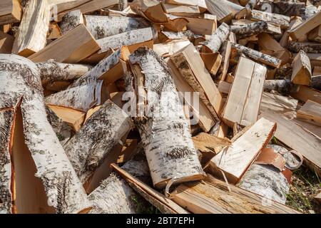 Brennholz für die Heizung des Ofens für den Winter auf dem Land. Abgebropfte Birkenstämme in einem großen Haufen Stockfoto