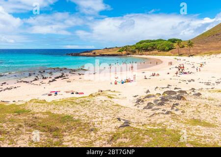 Touristen und lokale Rapa Nui Leute genießen den weißen Sandstrand und das türkisfarbene Wasser des Pazifischen Ozeans am Anakena Beach, Osterinsel, Chile. Stockfoto