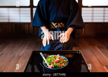 Traditionelles japanisches Zimmer im Machiya-Haus oder Ryokan-Restaurant mit schwarz lackiertem Holztisch und Salatgericht mit Mann in Kimono oder Yukata im Sitzen Stockfoto