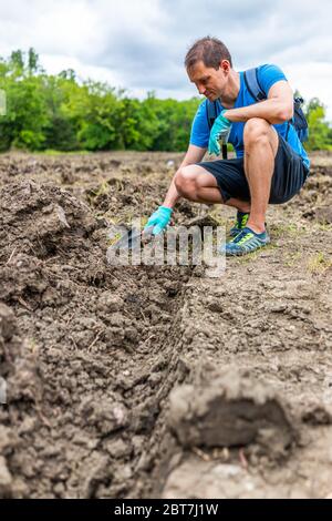 Mann graben mit Schaufel niedrigen Winkel Ansicht für Edelsteine in brauner Erde in Arkansas Dirt Landscape Wiese Feld in Crater of Diamonds State Park Stockfoto