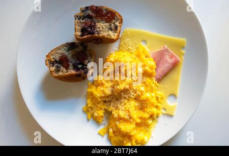 Rührei mit Schinken, Schweizer Käse und einem Blaubeer-Muffin Stockfoto