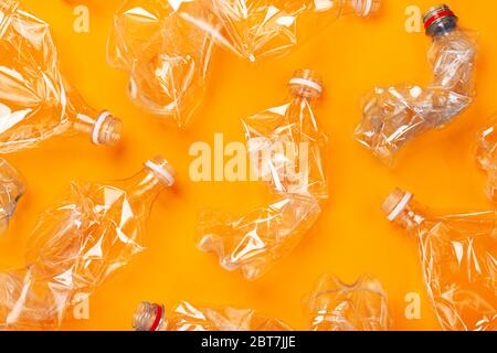 Viele gebrauchte Plastikflaschen auf orangefarbenem Hintergrund. Das Konzept der Verschmutzung des Planeten und der Ozeane durch Plastikmüll. Stockfoto
