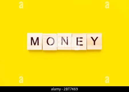 Holzblöcke mit dem Schriftzug Money auf gelbem Hintergrund. Business- und Finanzkonzept. Stockfoto