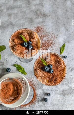 Nahaufnahme von traditionellen italienischen süßen Tiramisu Kuchen Dessert in Glas auf grau Stockfoto