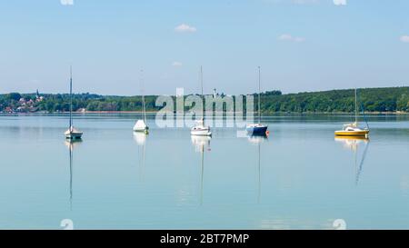 Panoramalandschaft mit ankenden Segelbooten. Farbenfrohe Aussicht auf den Ammersee. Symbol für Segeln, Segeln, Reichtum, Freizeitaktivitäten. Stockfoto