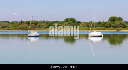 Schönes Panorama von Ammersee mit zwei Segelbooten. Mit Wasserspiegelungen. Üppiger, grüner Wald im Hintergrund. oberbayerische Landschaft. Stockfoto