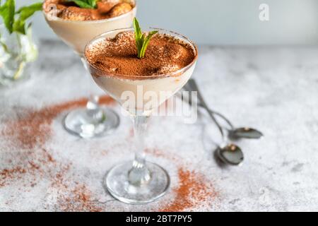 Klassisches Tiramisu in einem Glas auf grauem Hintergrund. Kopierbereich. Stockfoto