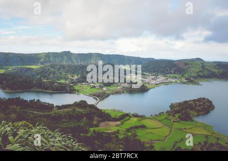 Herrlicher Blick auf die Lagoa Azul und das Dorf Sete Cidades vom Aussichtspunkt Miradouro do Cerrado das Freiras in Azoren, Portugal. Seen umgeben von grünen Feldern und Wald. Horizontales Foto. Stockfoto