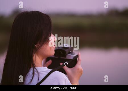 Porträt von schönen Lächeln asiatische Frau mit Mittelformat-Filmkamera mit grünen Natur Hintergrund halten Stockfoto
