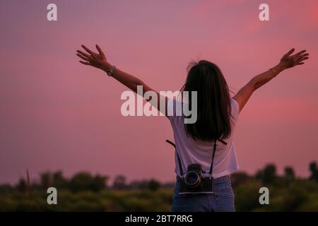 Porträt der schönen Freiheit asiatische Frau mit Mittelformat-Filmkamera mit bunten Sonnenuntergang Himmel Hintergrund halten Stockfoto