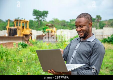 afrikanische landwirtschaftliche Geschäftsmann, mit einem Laptop auf einem Grundstück Stockfoto