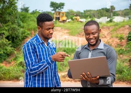 afrikanische Geschäftsleute, diskutieren und Vermessung eines Stückes Land, mit einem Laptop Stockfoto