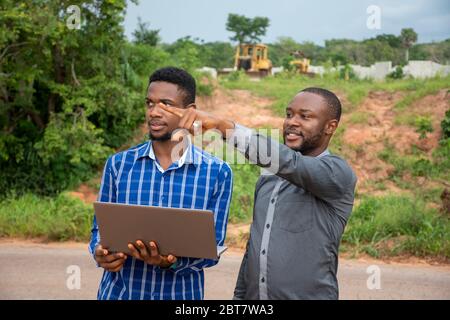 afrikanische Geschäftsleute, diskutieren und Vermessung eines Stückes Land, mit einem Laptop Stockfoto