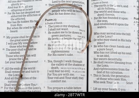 Die Heilige Bibel wurde in Psalm 23 von David mit einem kleinen Holzstab über dem Text eröffnet. Konzept: Versorgung und Schutz des Herrn in schwierigen Zeiten. Stockfoto