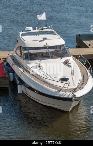 Luxusboot an einem sonnigen Tag, Blick von oben. Holzsteg am Fluss mit Seil und Ankerplatz. Stockfoto