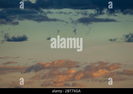 Blauer Himmel mit rötlichen Wolken für Reflexionen bei Sonnenuntergang und andere dunkle Wolken Stockfoto