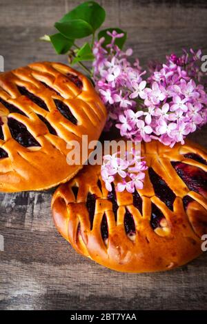 Brioche-Teig mit schwarzer Johannisbeere, mit violetten Fliederblüten, vertikales Bild Stockfoto