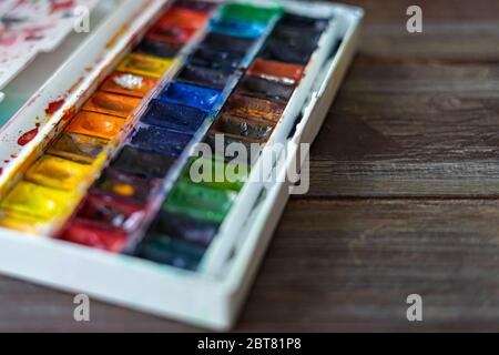 Set von Aquarellfarben und Pinsel für die Malerei Nahaufnahme. Selektiver Fokus. Holzhintergrund. Speicherplatz kopieren Stockfoto