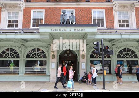 Fortnum & Mason Mitarbeiter mit Masken und Visieren begrüßen Kunden in seinem Flagship Store in Piccadilly, nachdem sie die Food Hall in London wiedereröffnet haben Stockfoto