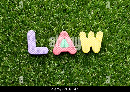Spielzeug Schaumstoff Brief im Wort Gesetz auf grünem Gras Hintergrund Stockfoto