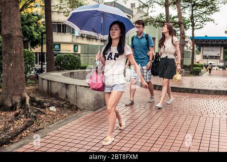 Taipei / Taiwan - 12. Dezember 2018: Taiwanesische junge Frau mit LÜCKE weißen Hemd zu Fuß mit blauen Regenschirm während sonnigen Tag im Park Stockfoto