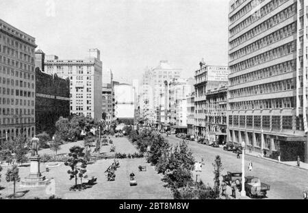 Blick Richtung Süden entlang der York Street, Sydney, Australien im Jahr 1938 mit Wynyard Square und der Statue von John Dunmore lang, einem Gründer der Presbyterian Church in Australien, auf der linken Seite und dem neuen mehrstöckigen New South Wales Railways Gebäude auf der rechten Seite. In den 82 Jahren seit der Aufnahme hat sich viel verändert, aber das Eisenbahngebäude ist noch im Einsatz. Dieses Bild wurde in einem Buch des Stadtverrats von Sydney veröffentlicht, um an den 150. Jahrestag der Gründung einer Nation zu erinnern. Stockfoto