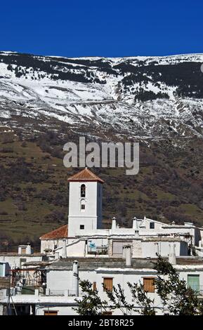 Blick über die Dächer des Dorfes auf die schneebedeckten Berge der Sierra Nevada, Capileira, Las Alpujarras, Provinz Granada, Andalucia, Spanien. Stockfoto