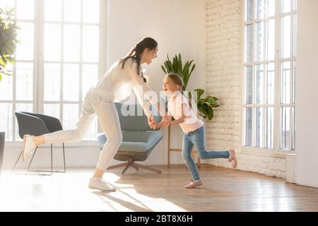 Überglücklich junge Mutter haben Spaß tanzen mit Tochter Stockfoto