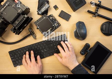 Die Hände wurden mit der Computertastatur durch verschiedene Geräte am Tisch abgeschnitten Stockfoto