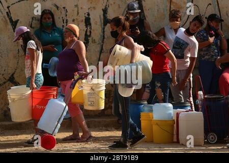 Caracas, Venezuela. Mai 2020. Die Leute stellen sich mit Kanistern und Schiffen an, um Wasser zu bekommen. In vielen Haushalten des Landes gibt es kein fließendes Wasser mehr. Die Wasserversorgung funktioniert teilweise nicht mehr. Die Coronavirus-Pandemie verschlimmert die Situation noch. Quelle: Pedro Rances Mattey/dpa/Alamy Live News Stockfoto