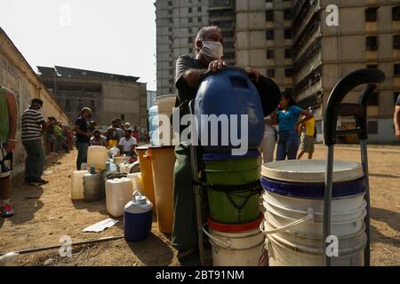 Caracas, Venezuela. Mai 2020. Im Bezirk Catia stehen die Menschen mit Kanistern und Schiffen an, um Wasser zu bekommen. In vielen Haushalten des Landes gibt es kein fließendes Wasser mehr. Die Wasserversorgung funktioniert teilweise nicht mehr. Die Coronavirus-Pandemie verschlimmert die Situation noch. Quelle: Pedro Rances Mattey/dpa/Alamy Live News Stockfoto