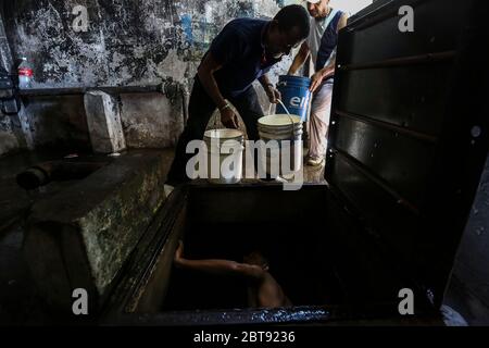 Caracas, Venezuela. Mai 2020. Männer sammeln Trinkwasser aus einem unterirdischen Brunnen im Bezirk Catia in Eimern. Viele Haushalte im Land haben kein fließendes Wasser mehr. Die Wasserversorgung funktioniert teilweise nicht mehr. Die Coronavirus-Pandemie verschlimmert die Situation noch. Quelle: Pedro Rances Mattey/dpa/Alamy Live News Stockfoto