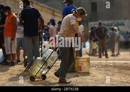 Caracas, Venezuela. Mai 2020. Die Leute stellen sich mit Kanistern und Schiffen an, um Wasser zu bekommen. In vielen Haushalten des Landes gibt es kein fließendes Wasser mehr. Die Wasserversorgung funktioniert teilweise nicht mehr. Die Coronavirus-Pandemie verschlimmert die Situation noch. Quelle: Pedro Rances Mattey/dpa/Alamy Live News Stockfoto