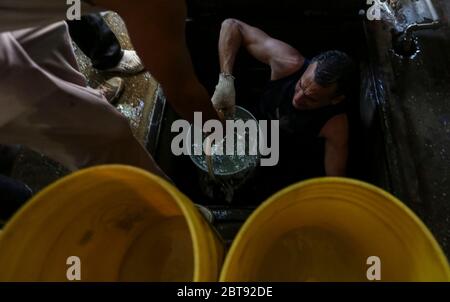 Caracas, Venezuela. Mai 2020. Männer sammeln Trinkwasser aus einem unterirdischen Brunnen im Bezirk Catia in Eimern. Viele Haushalte im Land haben kein fließendes Wasser mehr. Die Wasserversorgung funktioniert teilweise nicht mehr. Die Coronavirus-Pandemie verschlimmert die Situation noch. Quelle: Pedro Rances Mattey/dpa/Alamy Live News Stockfoto