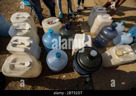 Caracas, Venezuela. Mai 2020. Die Leute stellen sich mit Kanistern und Schiffen an, um Wasser zu bekommen. In vielen Haushalten des Landes gibt es kein fließendes Wasser mehr. Die Wasserversorgung funktioniert teilweise nicht mehr. Die Coronavirus-Pandemie verschlimmert die Situation noch. Quelle: Pedro Rances Mattey/dpa/Alamy Live News Stockfoto