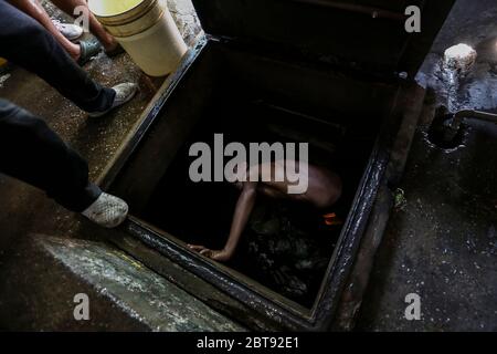 Caracas, Venezuela. Mai 2020. Männer sammeln Trinkwasser aus einem unterirdischen Brunnen im Bezirk Catia in Eimern. Viele Haushalte im Land haben kein fließendes Wasser mehr. Die Wasserversorgung funktioniert teilweise nicht mehr. Die Coronavirus-Pandemie verschlimmert die Situation noch. Quelle: Pedro Rances Mattey/dpa/Alamy Live News Stockfoto