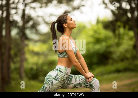 Hübsche junge Frau Stretching und atmen frische Luft in der Mitte des Waldes beim Training Stockfoto