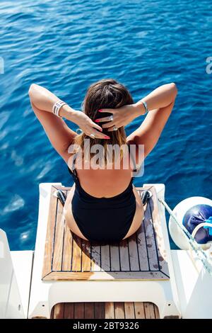 Rückansicht bei junger Frau, die sich an sonnigen Tagen auf der Yacht auf dem Meer entspannt Stockfoto