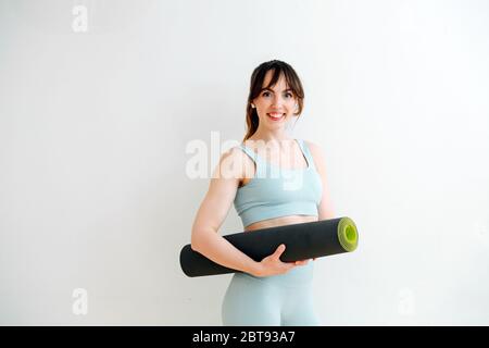 Vorbereitung auf das Training. Skinny Mädchen in einem Sweatsuit mit einer aufgerollten Matte Stockfoto