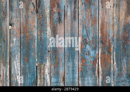 Textur von Holzlatten mit schälender Farbe. Alte hölzerne natürliche Hintergrund. Vertikale Platten mit verblichener Farbe. Zaunbretter in blau, braun und grau. Stockfoto
