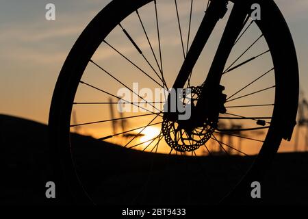 Profil eines Fahrradrades mit Scheibenbremsen bei Sonnenuntergang. Stockfoto