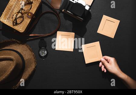 Sommer Reise flach legen Reisenden Accessoires set.Hand abholen Bilderrahmen auf schwarzem Holztisch mit harten Schattenleuchten Stockfoto