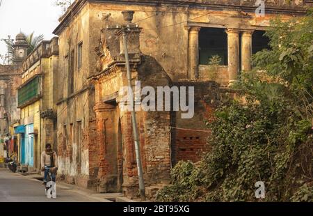 Murshidabad, Westbengalen/Indien - Januar 16 2018: Die alte bröckelnde Architektur auf den Straßen von Murshidabad. Ein Mann auf einem Fahrrad fährt durch. Stockfoto