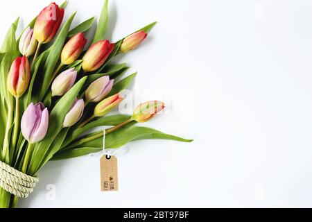 Schöne Bouquet von frischen bunten Blumen mit Geschenk-Tag auf weißem Hintergrund. Feier, Einladung, Überraschung, glücklicher Muttertag, Karte vom 8. März. Plakat, Banner, Blumengeschäft, Mock-up, Brett. Stockfoto