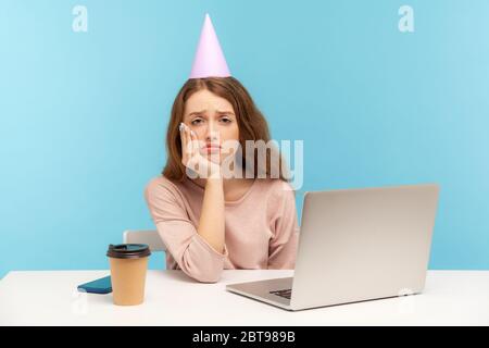 Gelangweilte verärgerte Frau, Büroangestellte mit Party-Kegel suchen mit Depression Frustration, Geburtstag allein während Quarantäne zu Hause feiern, arbeiten Stockfoto